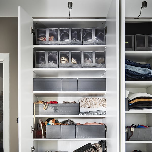 Closet with white shelves, grey SKUBB boxes for shoe storage, some folded clothes.
