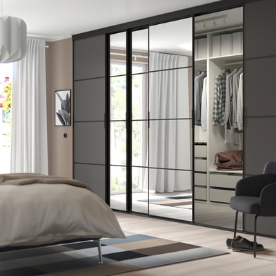 Modern bedroom with mirrored closet, neutral furniture, and minimalist decor.