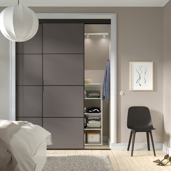 Modern bedroom with SKYTTA sliding closet doors, black chair, minimalist decor.