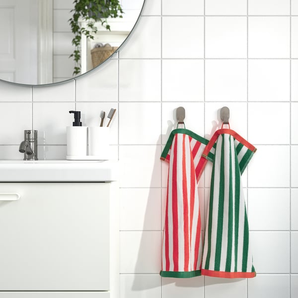 Bright red & green-striped SLÅNHÖSTMAL towels hang beside white sink and mirror.