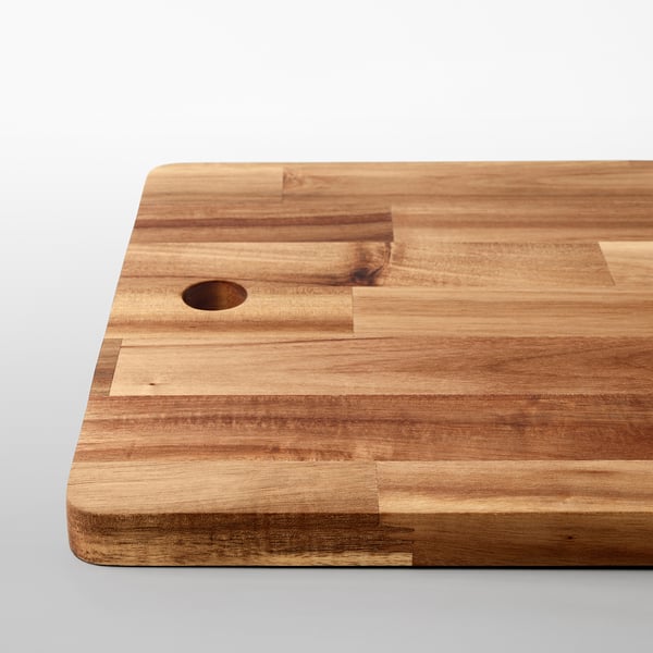 Wooden cutting board made of solid acacia, featuring a smooth surface and a small handle hole, ideal for food prep.