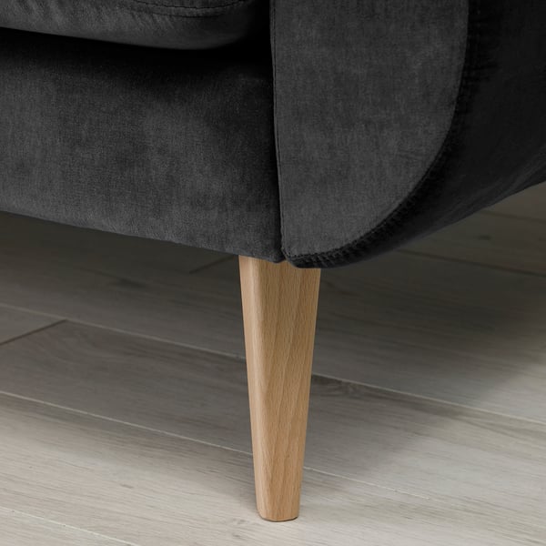 Dark grey modern sofa with sleek, wooden cone legs and cosy cushions.