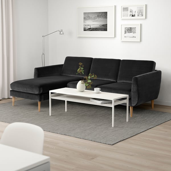 Modern living room with retro-style sectional sofa, coffee table, wall art, lamp, and rug - cosy minimalism.