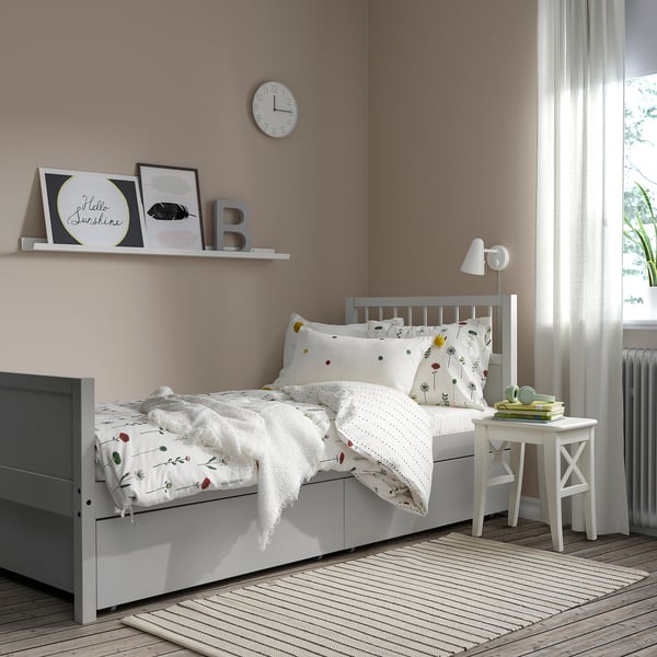 Cosy bedroom with grey SMYGA bed, floral bedding, bedside table.