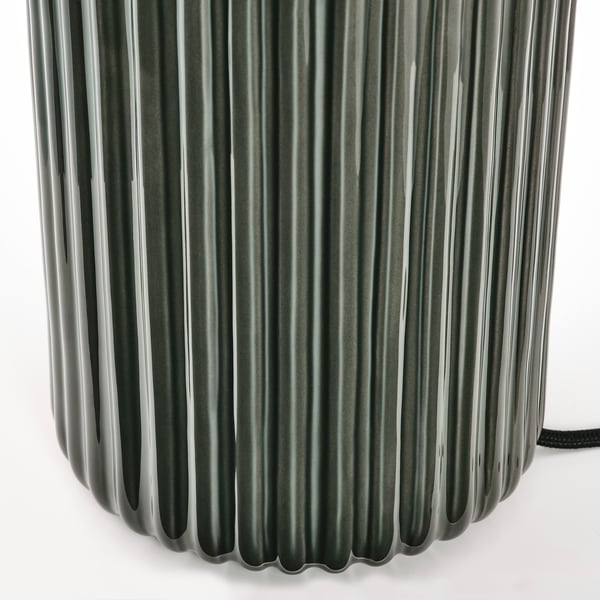 A metallic, cylindrical lamp with vertical fluted design reflecting light, showcasing high-quality craftsmanship.
