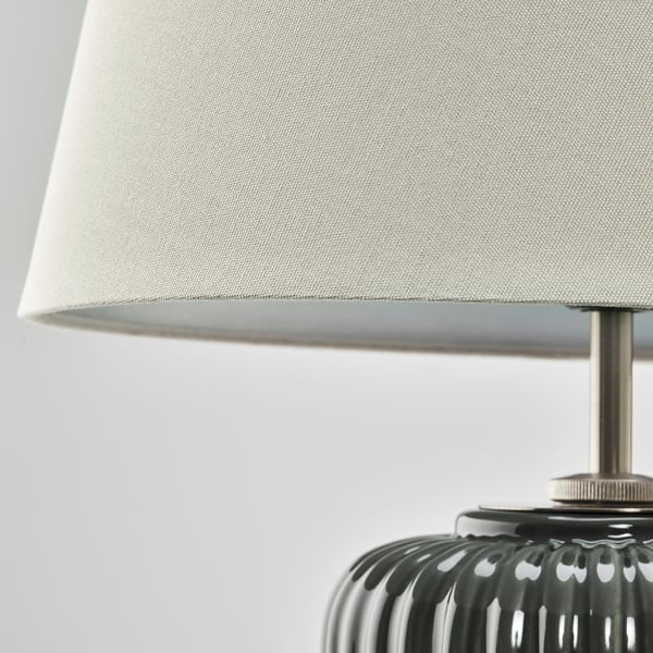 Close-up of lamp with textured base and beige shade.
