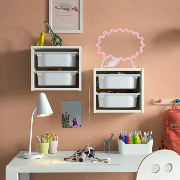 Kids desk with lamp & shelves. Neon pink lamp, art supplies, playful decor.