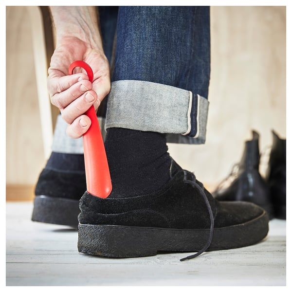 Person holding red shoehorn with loop and straight edge.