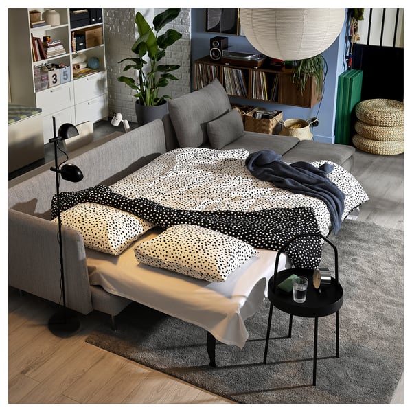 Modern grey sofa bed with polka dot pillows in stylish living room.