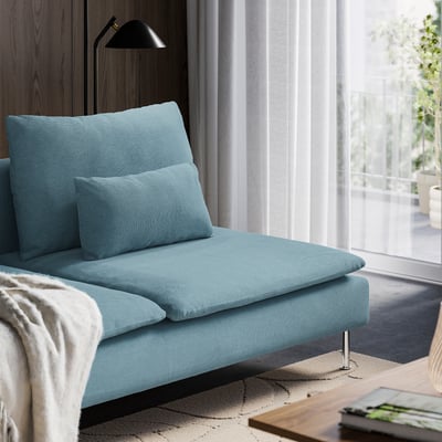 Modern living room with light blue sofa, large cushions, and wooden cabinet. Natural light through curtains.
