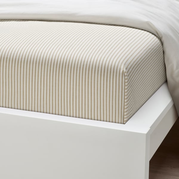 Crisp, striped white bed sheet on clean, white bed frame, inviting rest.