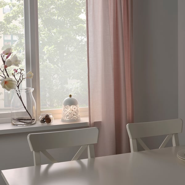 Window with sheer curtains, lamp, vase of flowers, grey chair.