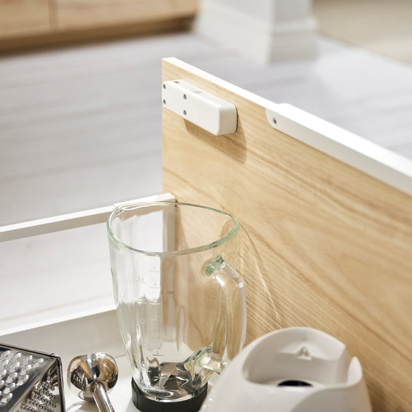 Wooden cutting board with a transparent blender where white tags are attached.