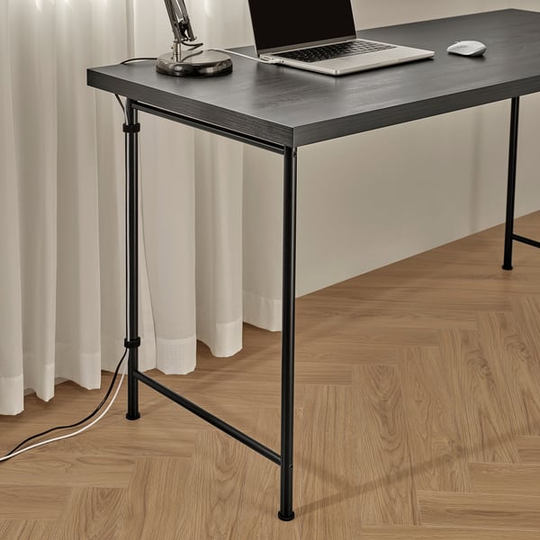Modern desk setup with laptop, mouse, and lamp, featuring adjustable legs for stability on uneven floors, black metal frame, and sleek wooden top.
