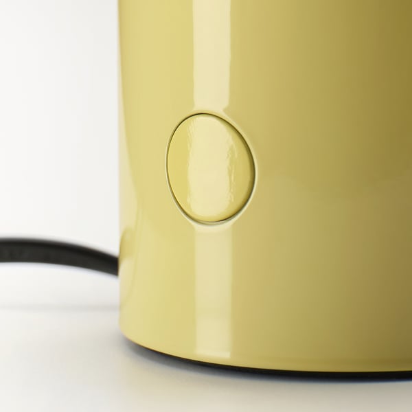 A close-up of a sleek, yellow table lamp with a shiny surface and a circular power button.