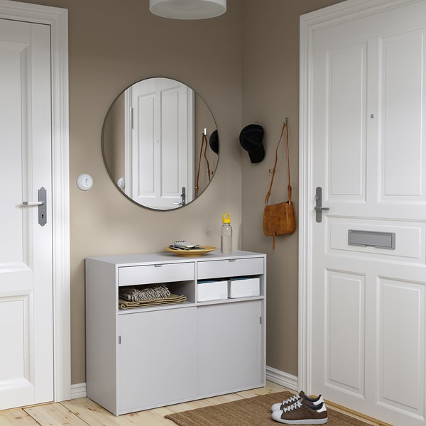 Grey SPIKSMED cabinet with sliding doors, corner placement with mirror and rug.