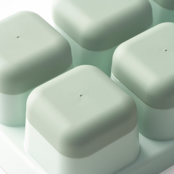 Four pastel green ice cube trays stacked neatly, each with a lid, showcasing quality and design.