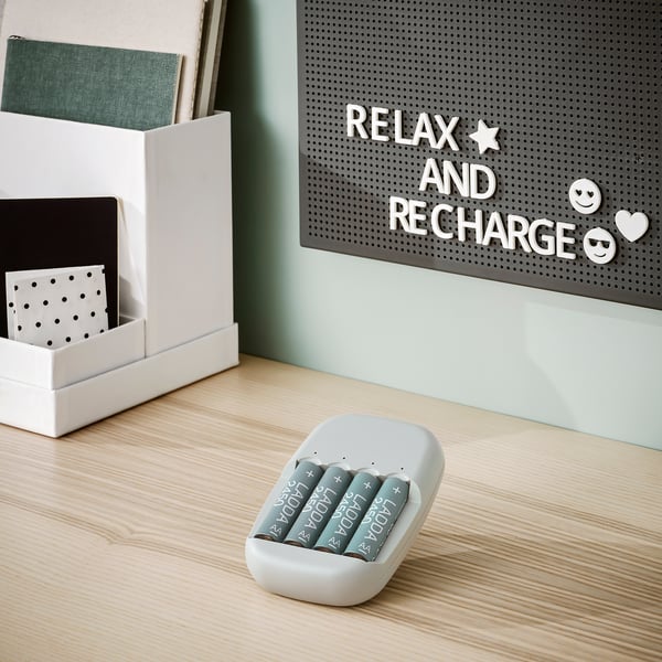 Charger & batteries on desk, organiser with notebooks, letterboard says relax, recharge, smile.