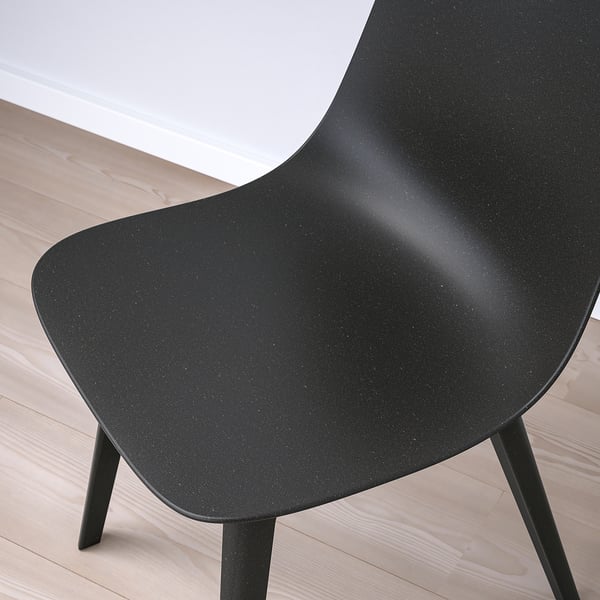 Black chair on light wooden floor, showing sleek design and sturdy build.