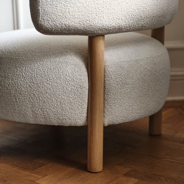 A light grey armchair with wooden legs. The soft, rounded upholstery creates a comfortable seating experience.