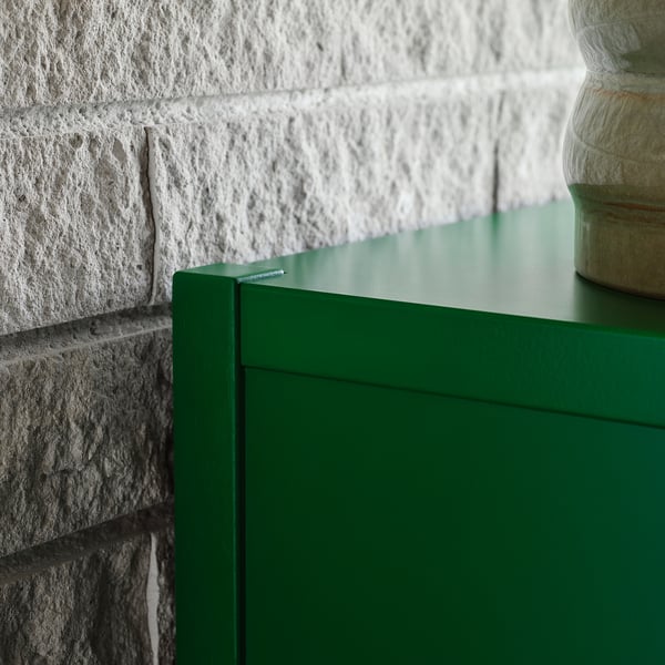 Bright green cabinet next to a white brick wall.