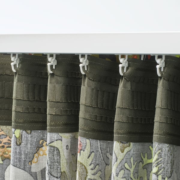 Curtains with nature pattern, pleated, white hooks, filtering daylight.