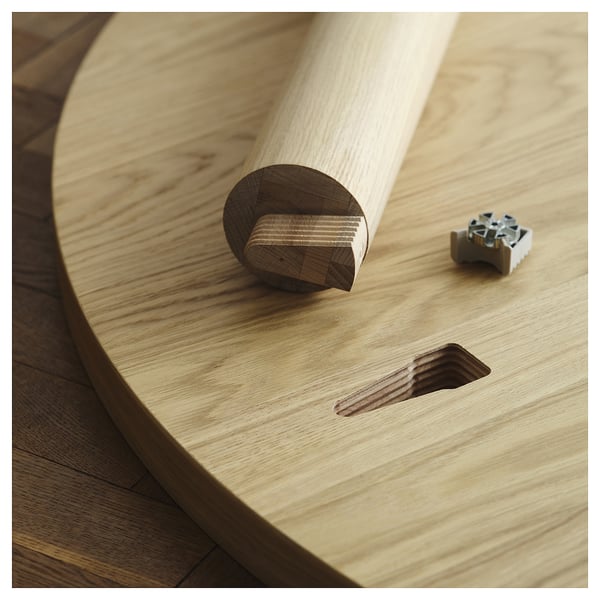 Image shows a wooden table leg with a metal connector near a cut-out.