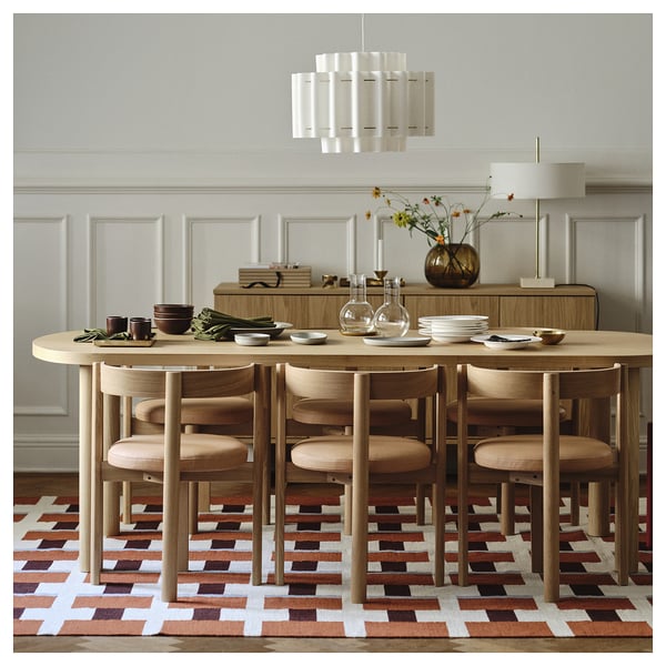 Modern dining setup with light wood table, matching chairs, pendant light, and sideboard. Natural oak finish and scandinavian design.