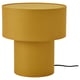A mustard yellow STOCKHOLM 2025 table lamp with a cylindrical shape and linen fabric shade, giving a soft warm light.