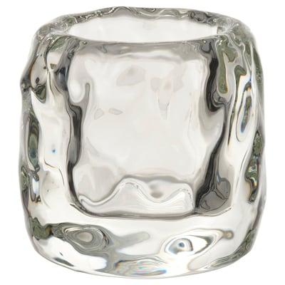 STOCKHOLM 2025 ice cube-shaped tealight holder, clear glass, thick design, elegant, emits warm glow.
