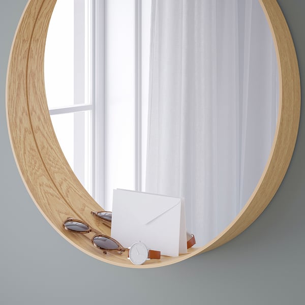 Mirror with wooden frame and shelf items; reflects curtains.