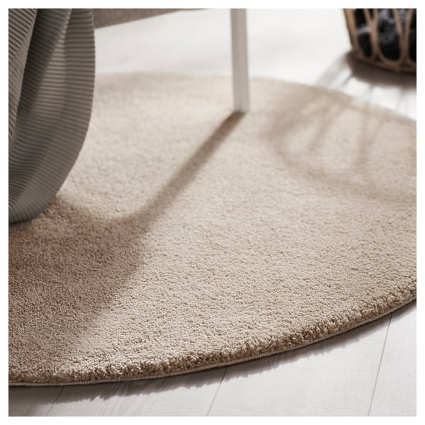 Beige round rug, soft with textured pile, placed on light floor, enhancing room comfort.