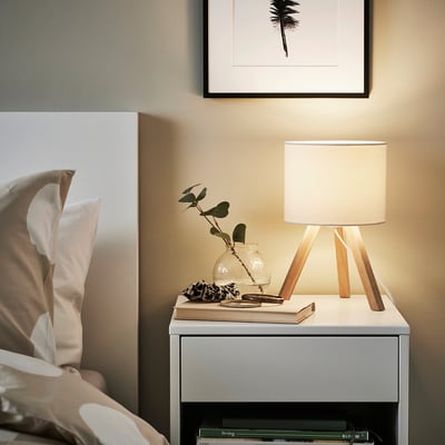 Cosy bedside: STORSEGEL lamp, books, plant, palm leaf art.