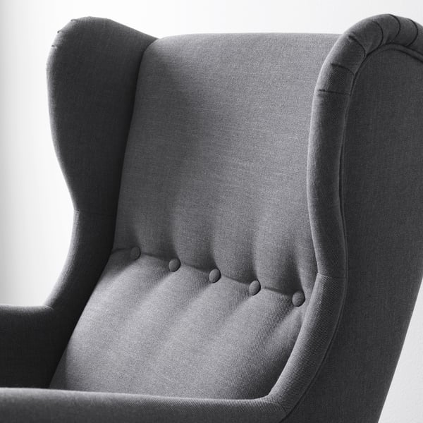 Elegant wingback chair close-up, showcasing high-quality fabric. Detailed stitching and robust construction.