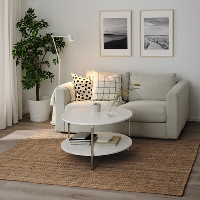 Minimalist living room with grey couch, white table, jute rug, decor, and STRÖG rug.