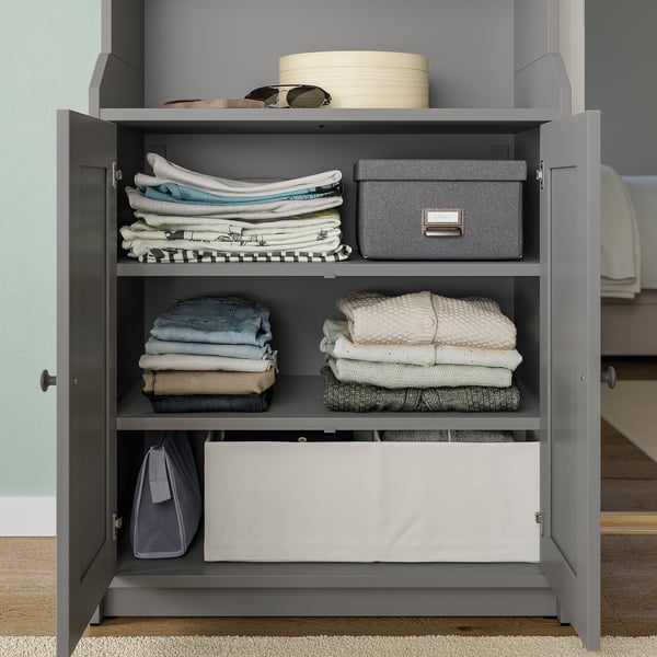 Gray STUK storage cabinet with folded clothes, boxes, and accessories.