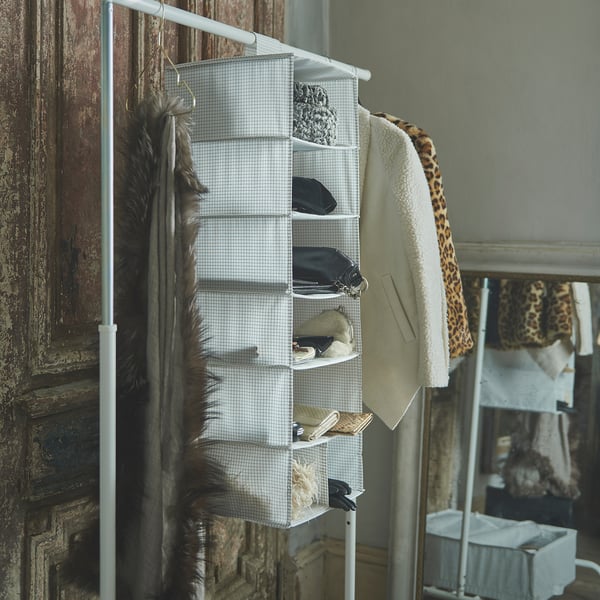 White hanging shelf organiser with grid pattern by STUK, holds various items in a closet space.