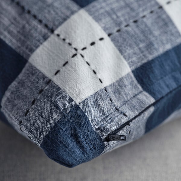 Close-up of a dark blue chequered cushion cover with visible stitching and a zip.