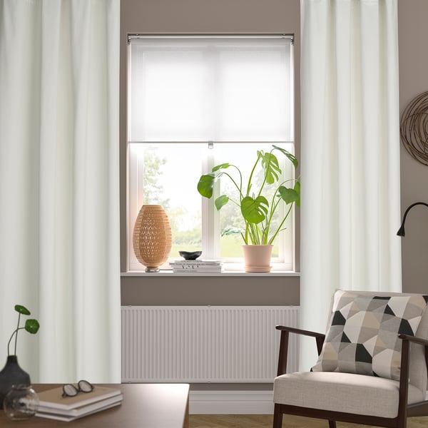 Cosy living room with window, plant, chair, & books.