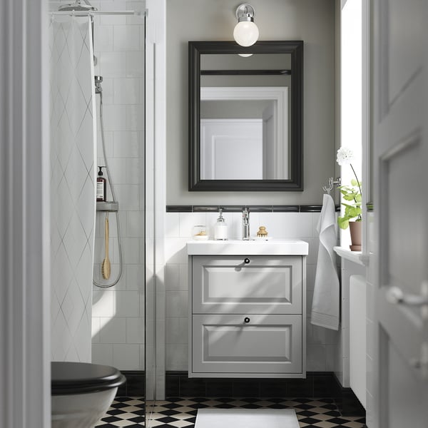 Modern bathroom with TÄNNFORSEN light grey vanity, large mirror, shower, towel, plant, and chequered floor.