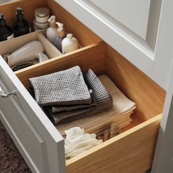 Bathroom drawer organiser with towels, bottles, and brushes.