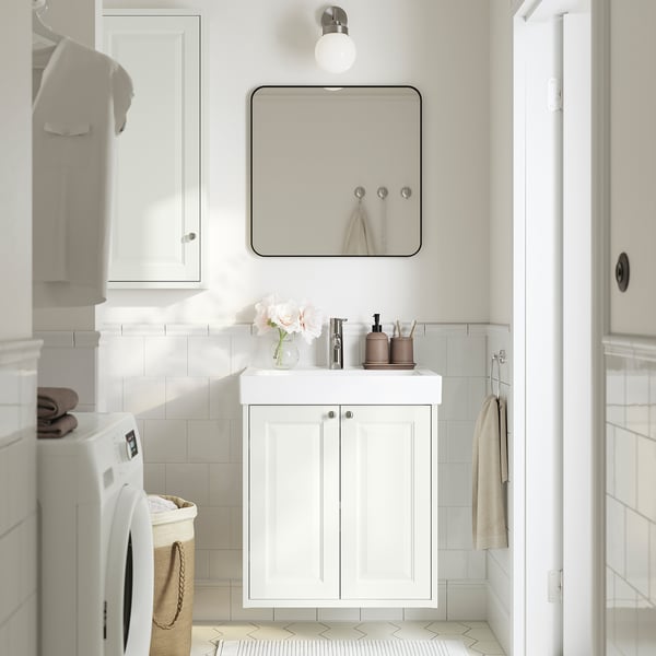White vanity with sink, mirror, and storage in bathroom.