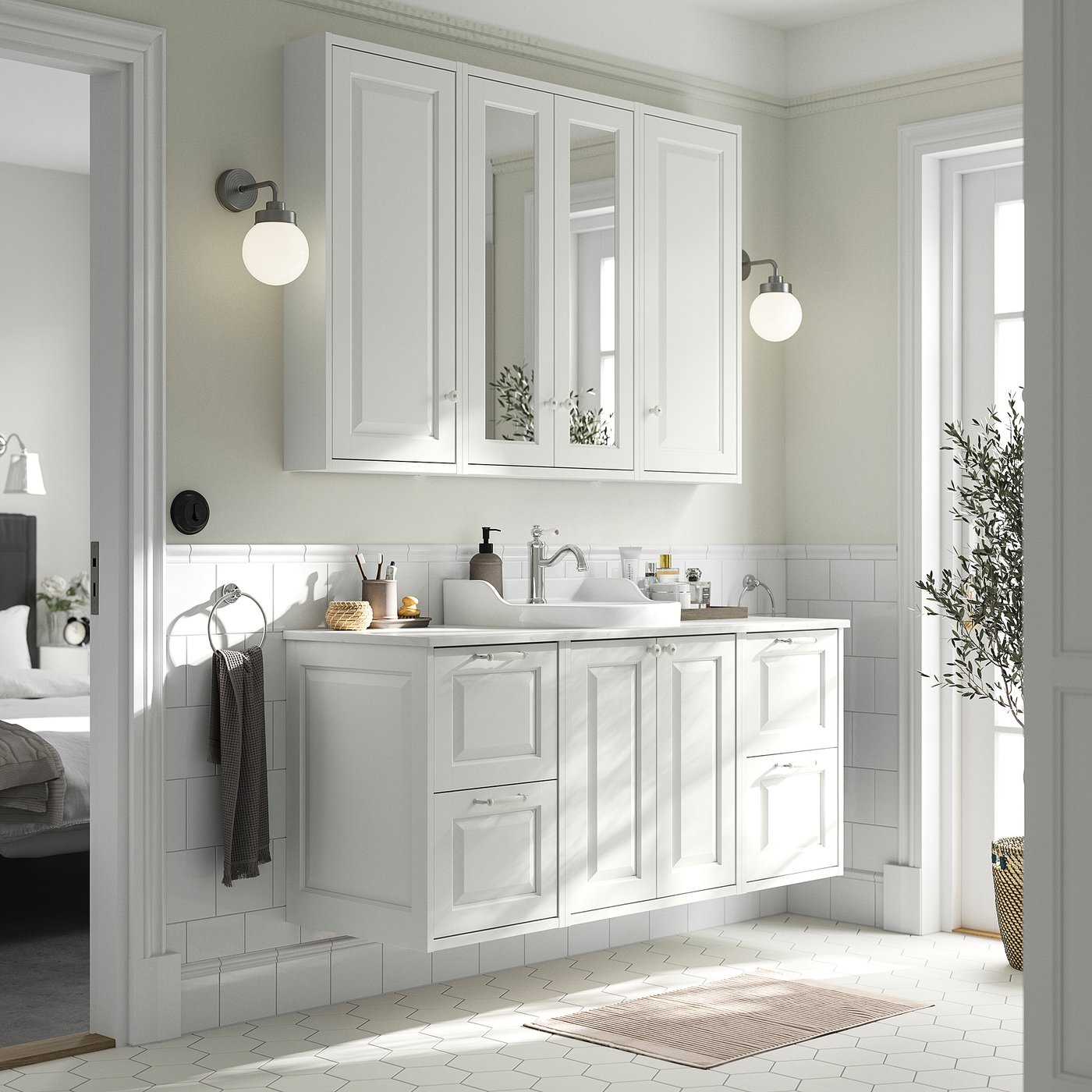 White bathroom vanity with two drawers, two doors, and a sink. Mirrors above, wall-mounted lights, grey towels, and a rug.