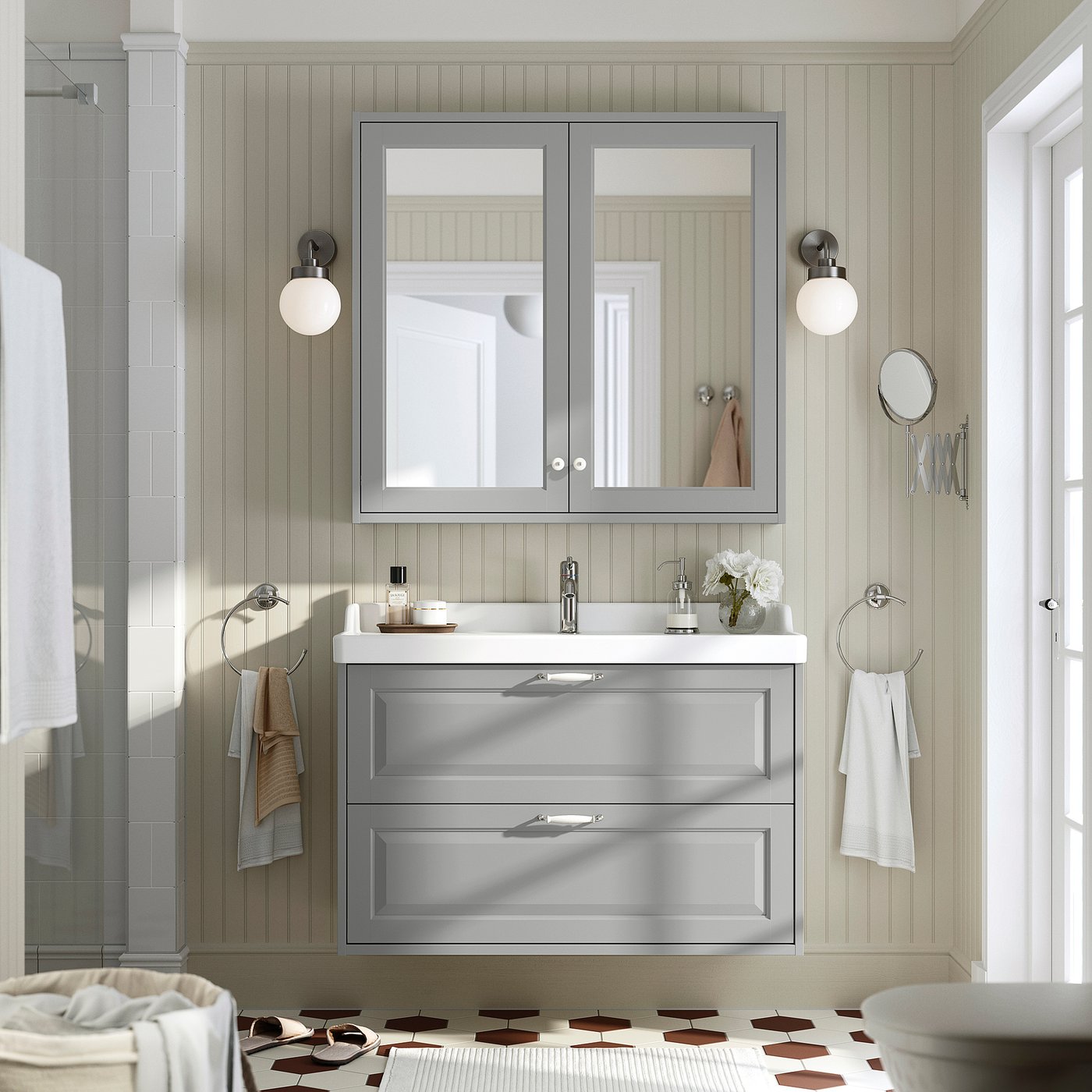 Gray TÄNNFORSEN bathroom vanity with mirror cabinet, sleek drawers, chrome fixtures, and round wall lights against vertical panel walls.