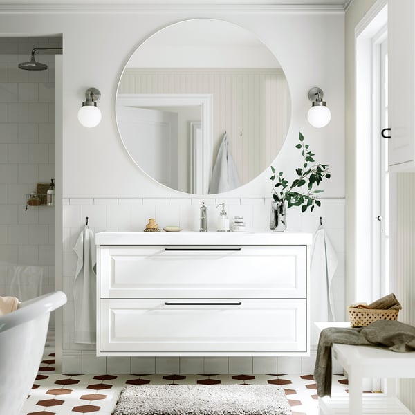 Stylish bathroom with TÄNNFORSEN vanity, mirror, and drawers. White tiles, patterned floor, green plants. Modern and classic blend.