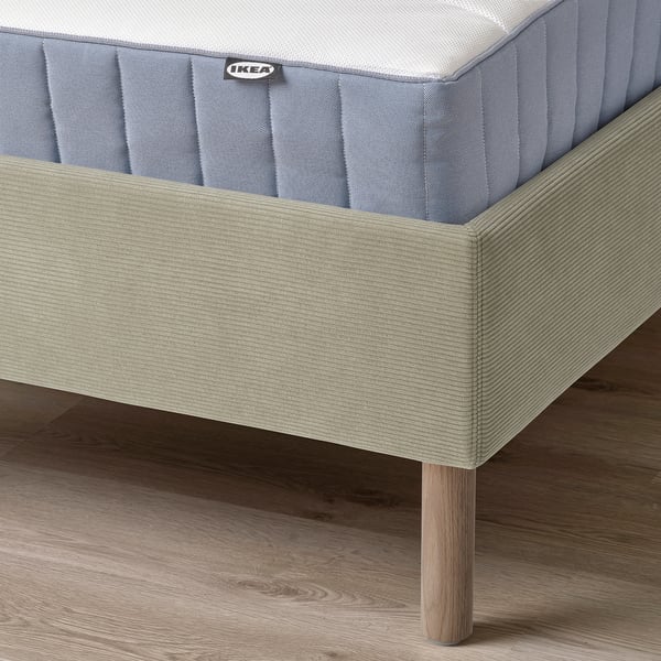 A modern bed frame with a padded headboard and wooden legs, designed for comfort and easy cleaning.