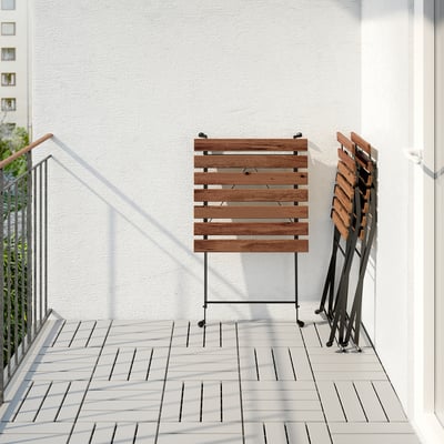 Balcony with foldable acacia hardwood table and stacked chairs, ideal for space-saving.