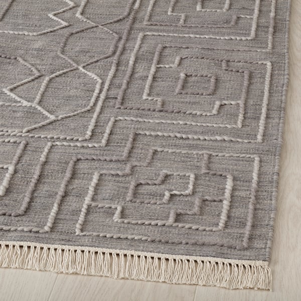 This rug a raised geometric wool design, expertly handwoven with fringe edges. Ideal for durability and style.