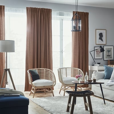 Modern living room with TIBAST curtains, wicker chairs, white couch, and table décor. Floor lamp, wall art, light wood floor, shaggy rug.