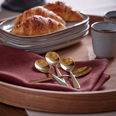 A serving tray holds plates of pastries and brass-colored TILLAGD spoons.